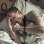 zaburzenia snu; bezsenność; Mężczyzna leży w łóżku, ziewając i zakrywając twarz, z nałożoną tarczą zegara.