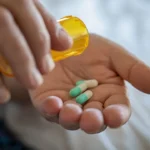 Wpływ antydepresantów na osobowość: Osoba dawkuje dwie pigułki leku na rękę z żółtego pojemnika