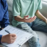 skala depresji Hamiltona: Kobieta wypełnia formularz, a mężczyzna gestykuluje dłońmi podczas sesji psychoterapii.